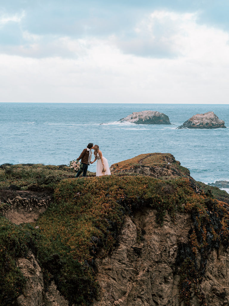 Oceanside elopement photo of a couple kissing on the cliffs