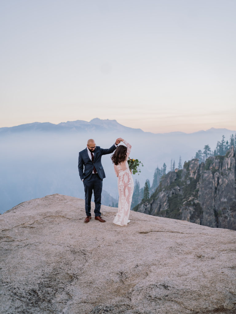 Groom twirls bride on a cliff in Yosemite
