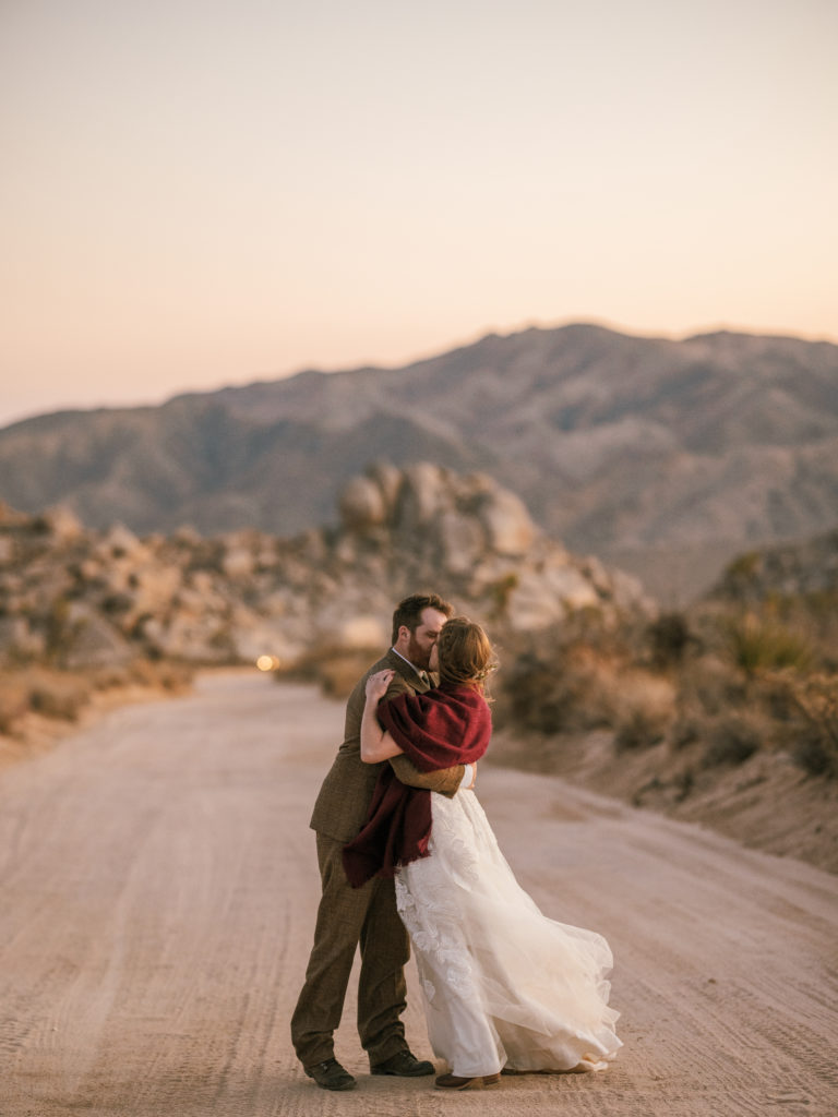 Couple kisses on a dirt road in Joshua Tree