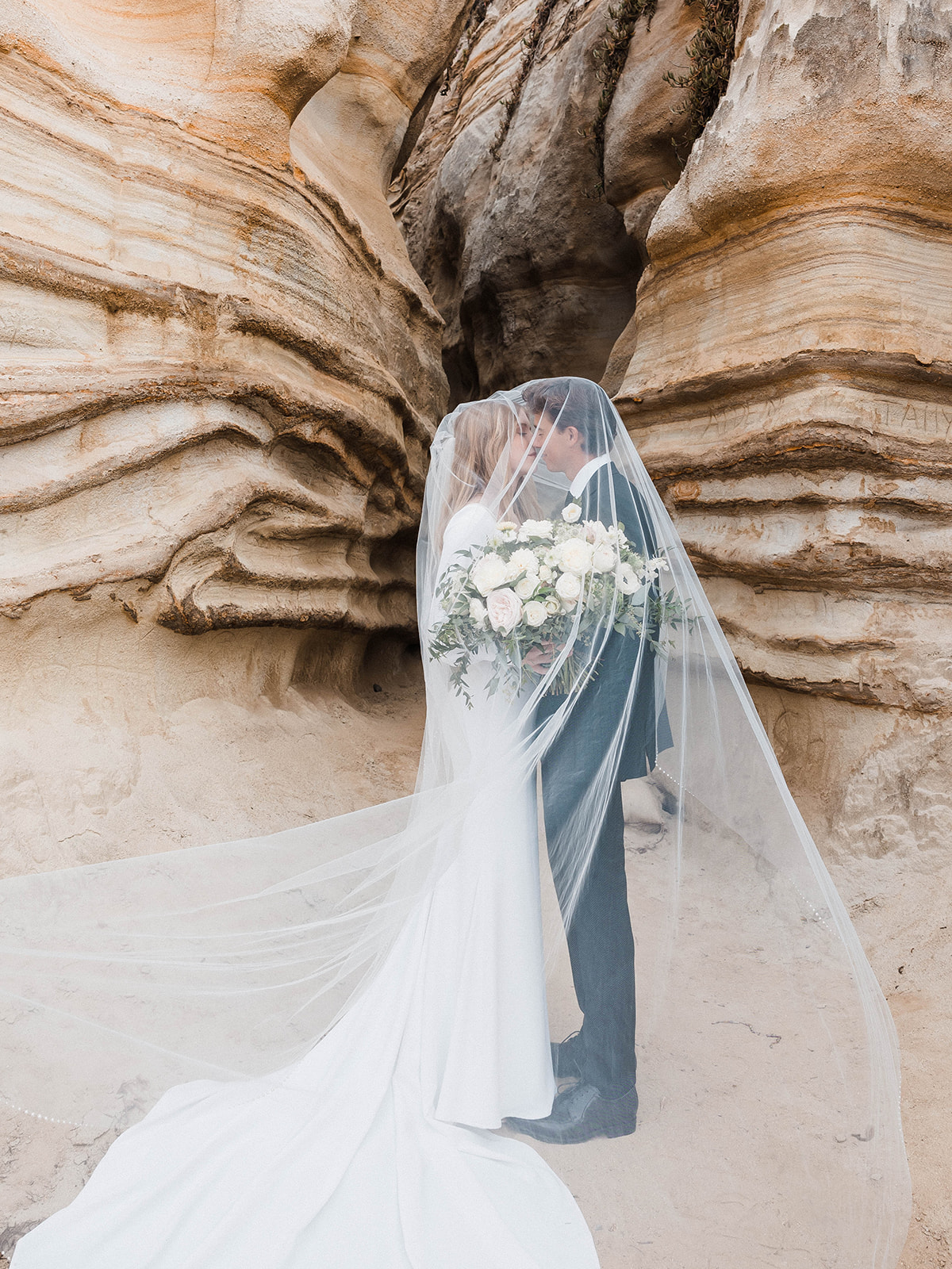Bride and Groom kissing beneath the cliffs